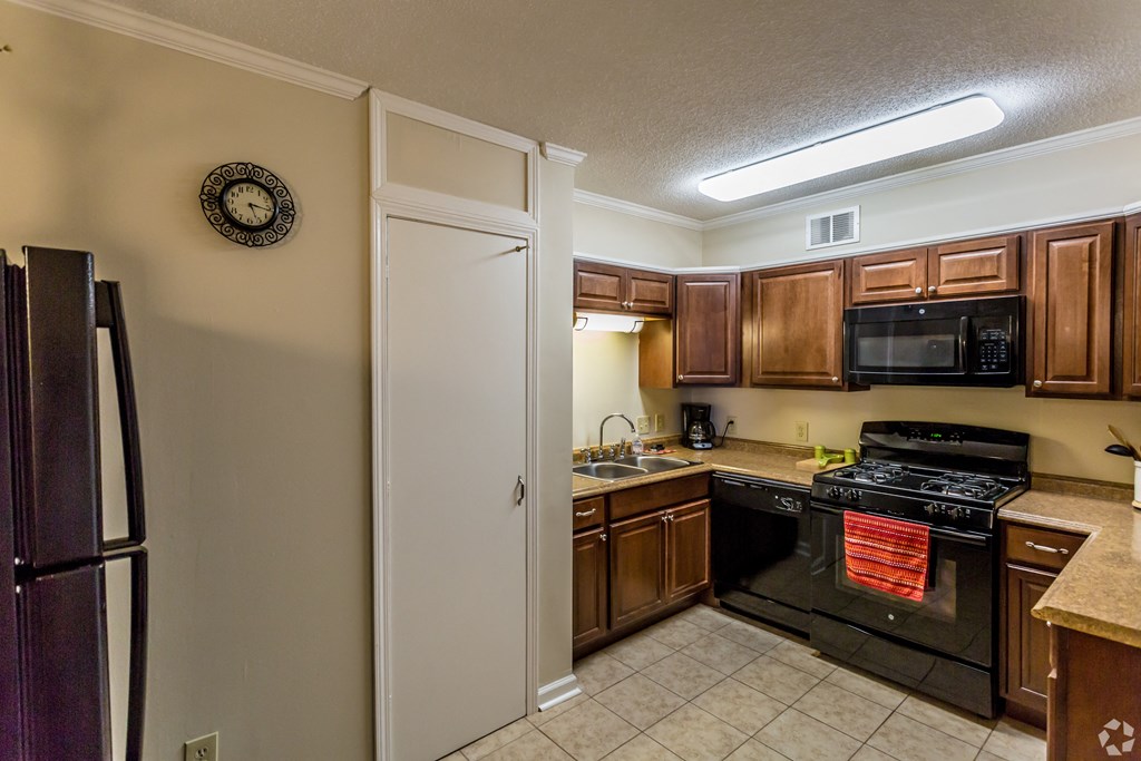 a kitchen with wood cabinets and black appliances and a refrigerator