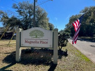 a sign that says magnolia place with an american flag in the background