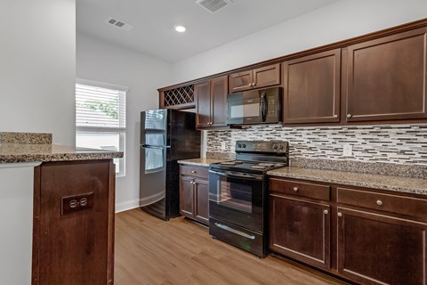 an updated kitchen with wood cabinets and granite counter tops and black appliances