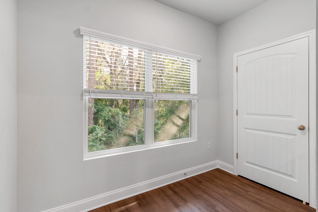 a bedroom with a large window and hardwood floors