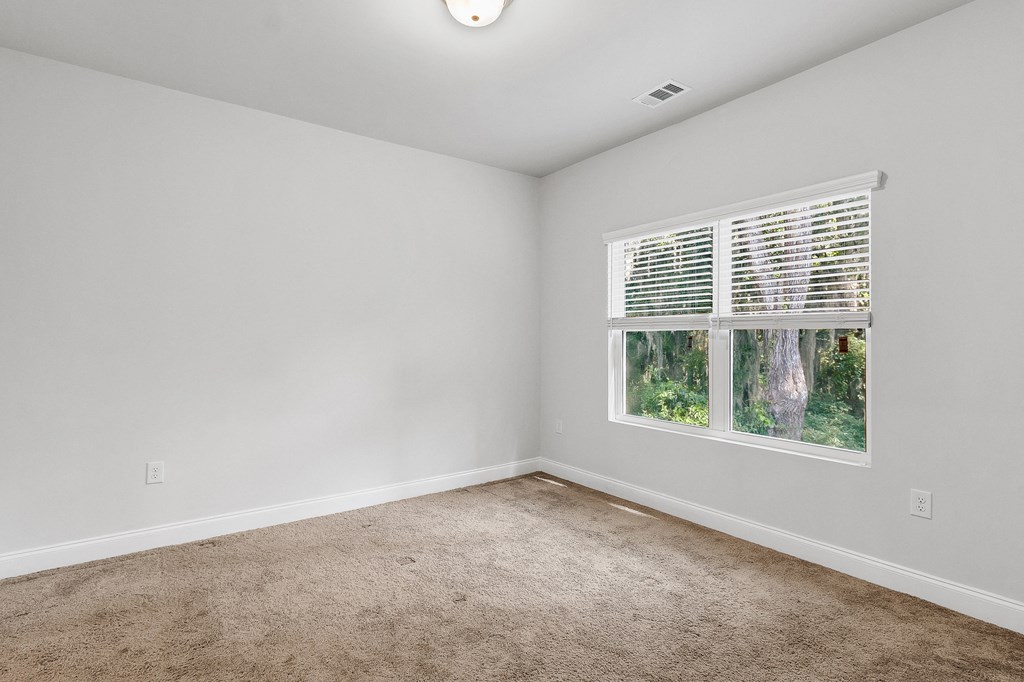 a bedroom with a large window and a carpeted floor