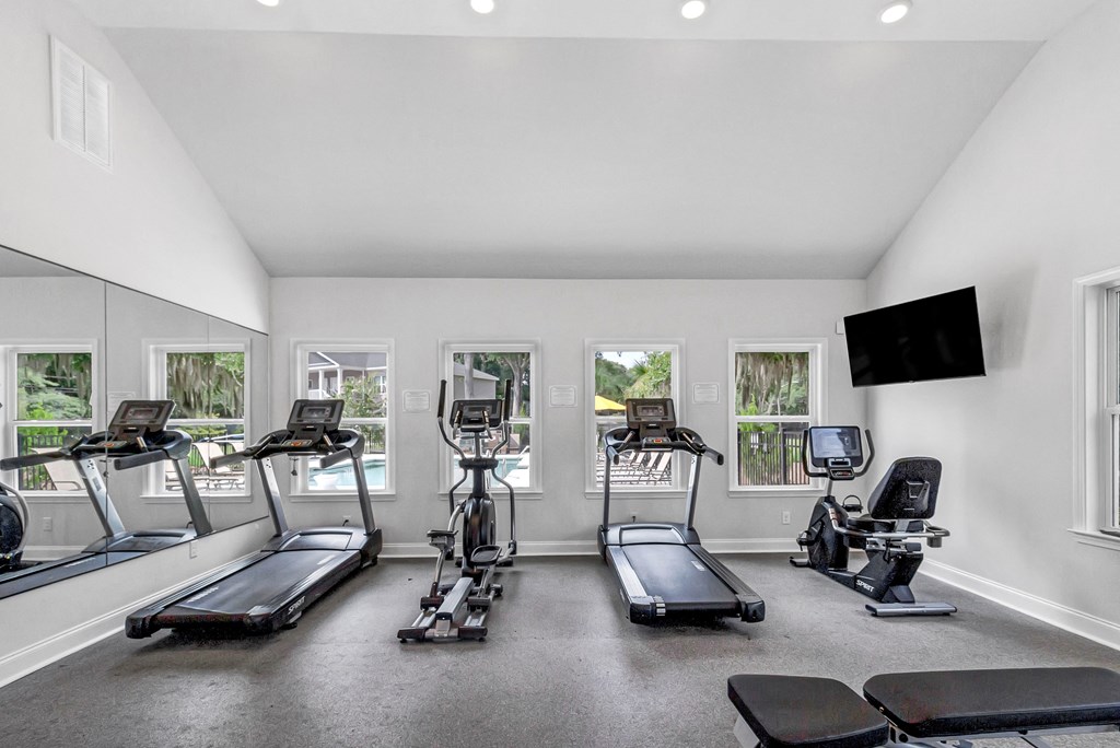 a gym with cardio equipment and a flat screen tv