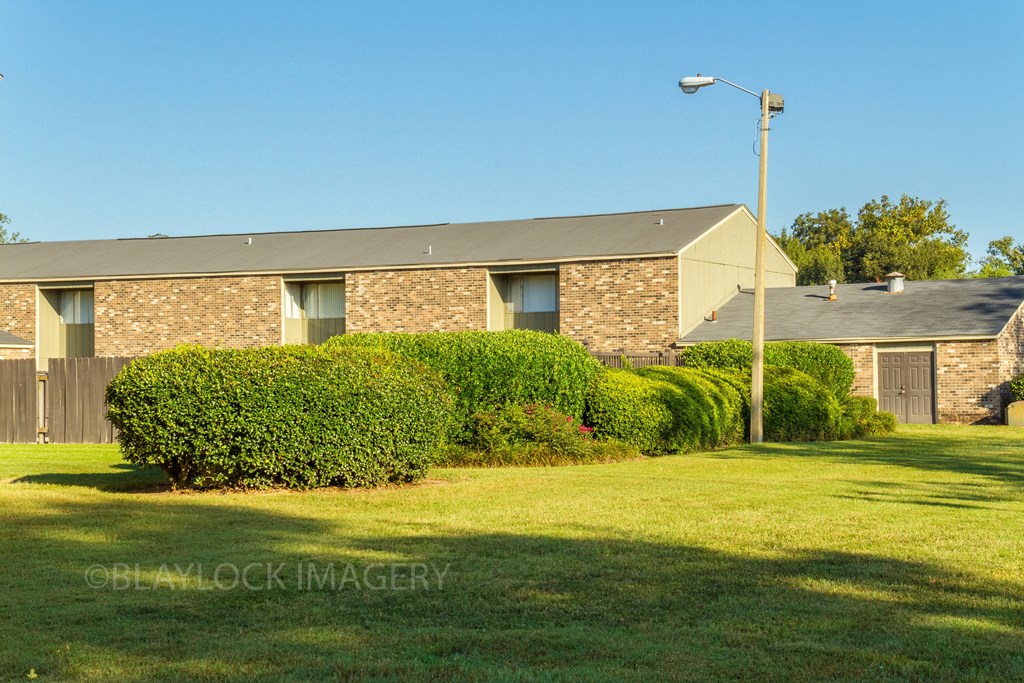 a brick house with a grey roof and a green lawn in front of it