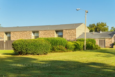 a brick house with a grey roof and a green lawn in front of it