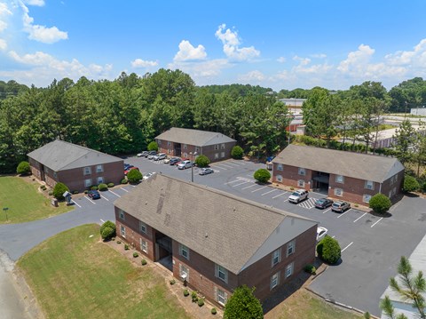 A parking lot is in front of a building surrounded by trees.