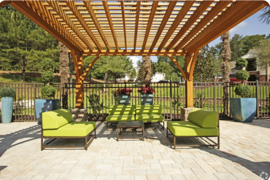 A wooden pergola with green cushioned seating.