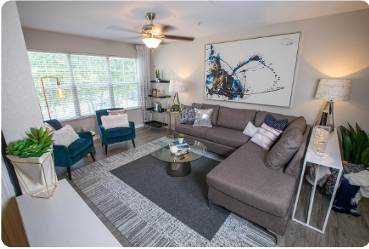 A living room with a grey couch, a coffee table, and a ceiling fan.