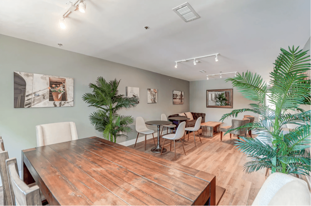 a dining room with a wooden table and chairs and plants