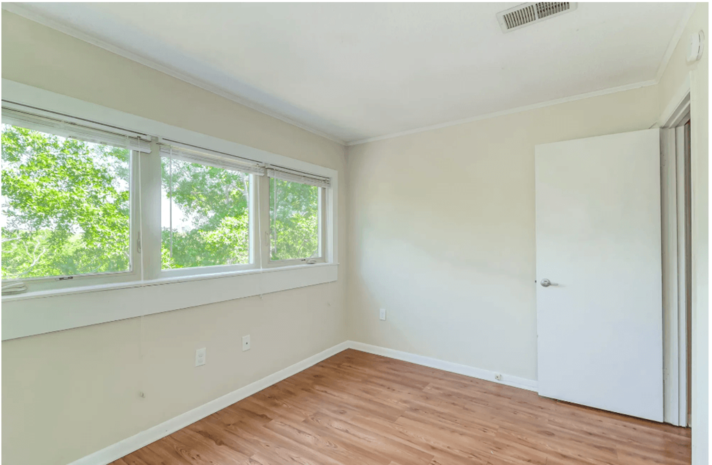an empty room with a door and three windows
