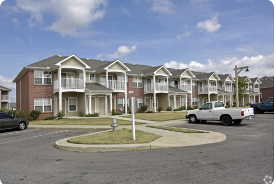 A row of houses with cars parked in front.