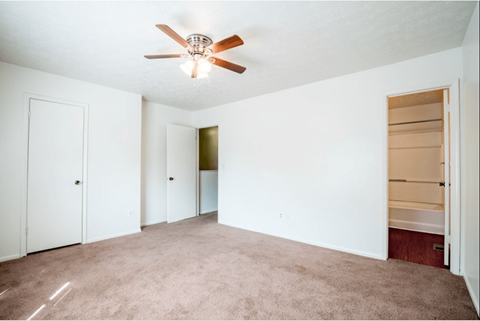 A room with a ceiling fan and carpeted floor.