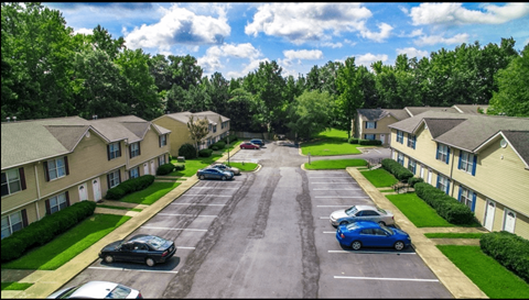 A parking lot in front of apartment buildings on a sunny day.