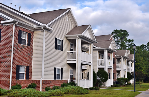 Apartment building with balconies and a cloudy sky.