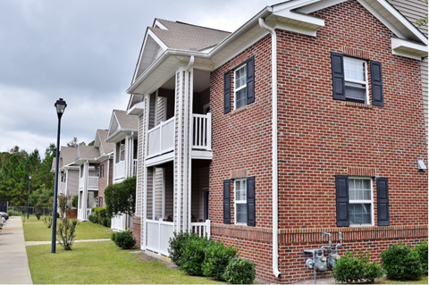 A row of red brick houses with white trim and black shutters.