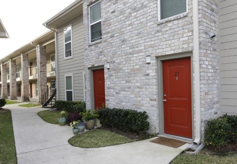 A red door is on the right side of a grey building.