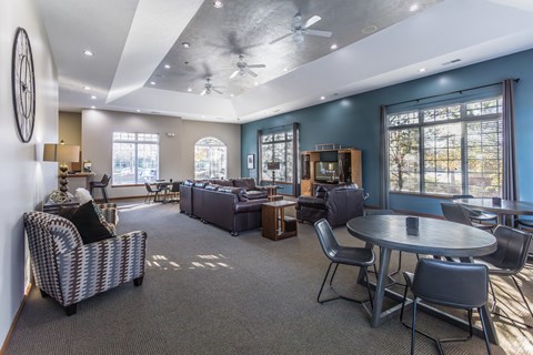 A spacious living room with a ceiling fan and a variety of seating options.