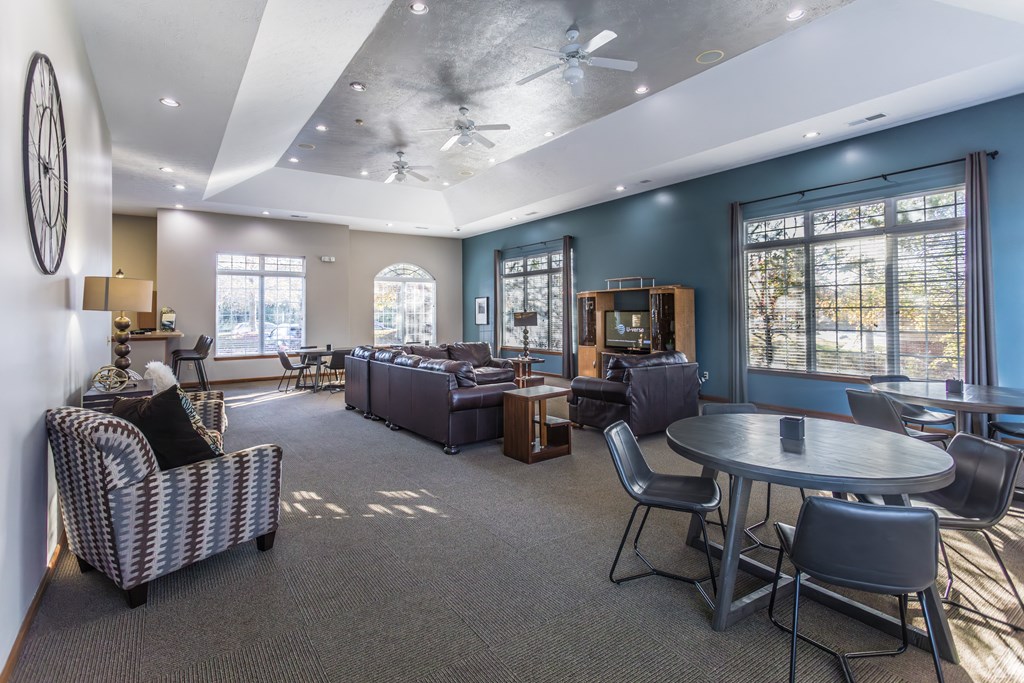 A spacious living room with a ceiling fan and a variety of seating options.