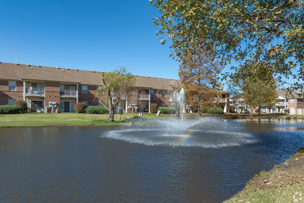A fountain in the middle of a lake with a rainbow in the water.