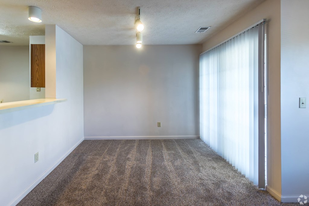 A room with a carpeted floor and a window with curtains.
