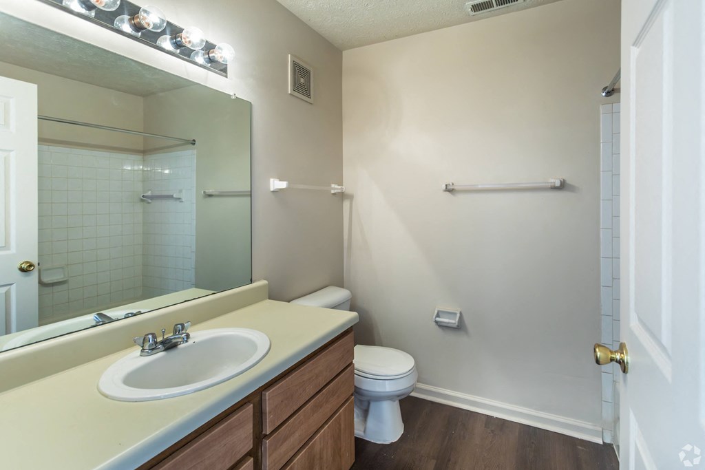 A white toilet sits in a bathroom next to a sink and a mirror.
