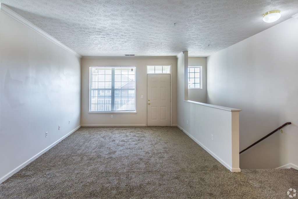 A room with a carpeted floor and a window with blinds.