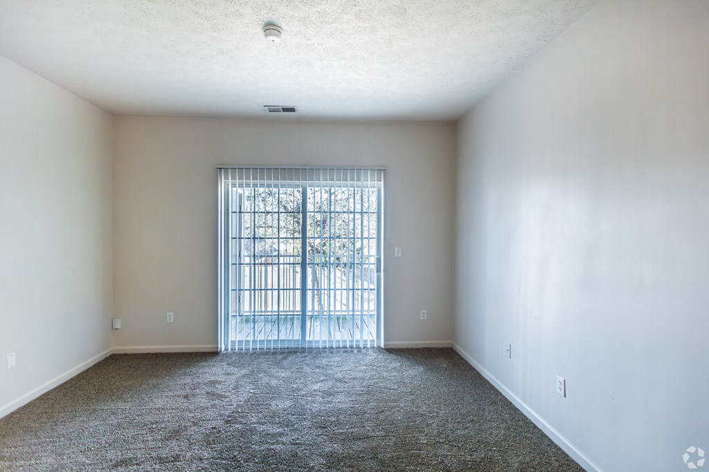 A room with a carpeted floor and a metal gate in the door.