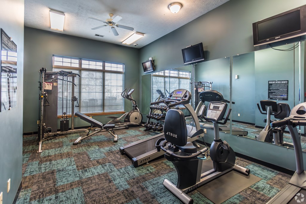 A gym with a variety of equipment including treadmills, weights, and exercise machines.