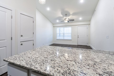 A spacious room with a granite countertop and a ceiling fan.