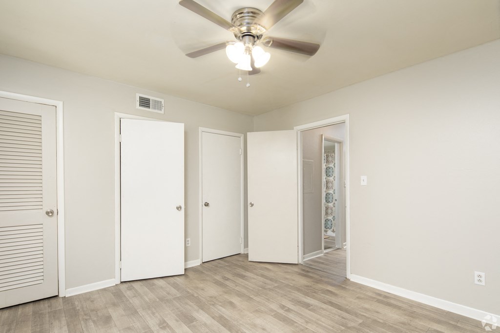 the living room of an empty apartment with a ceiling fan