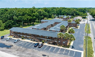 a large brick building with a gray roof and a parking lot in front of it