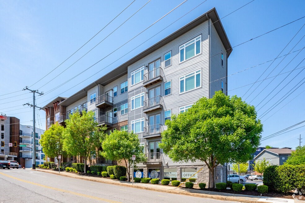an apartment building on the corner of a street with trees