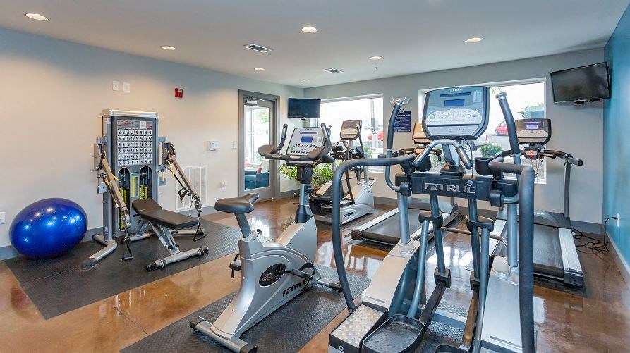 a gym with various exercise equipment and a tv