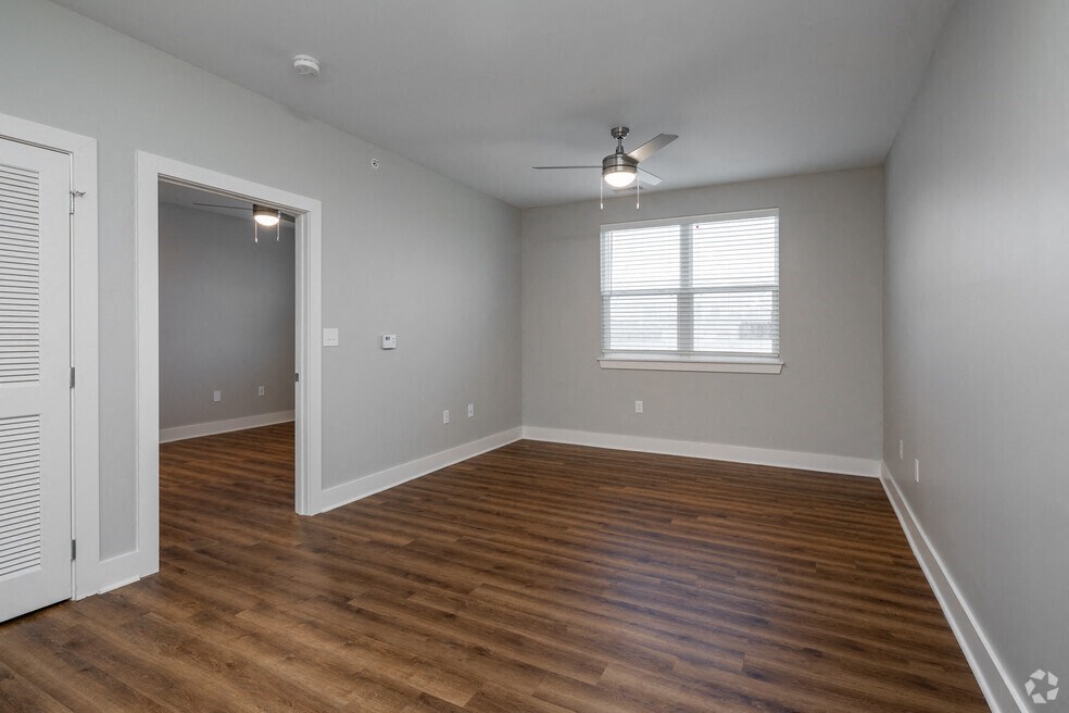 an empty living room with wood floors and a ceiling fan