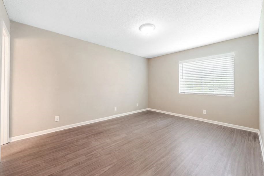 an empty living room with a window and wooden floors