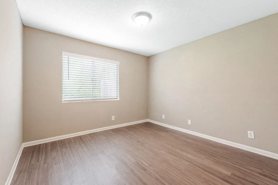 an empty living room with wood floors and a window