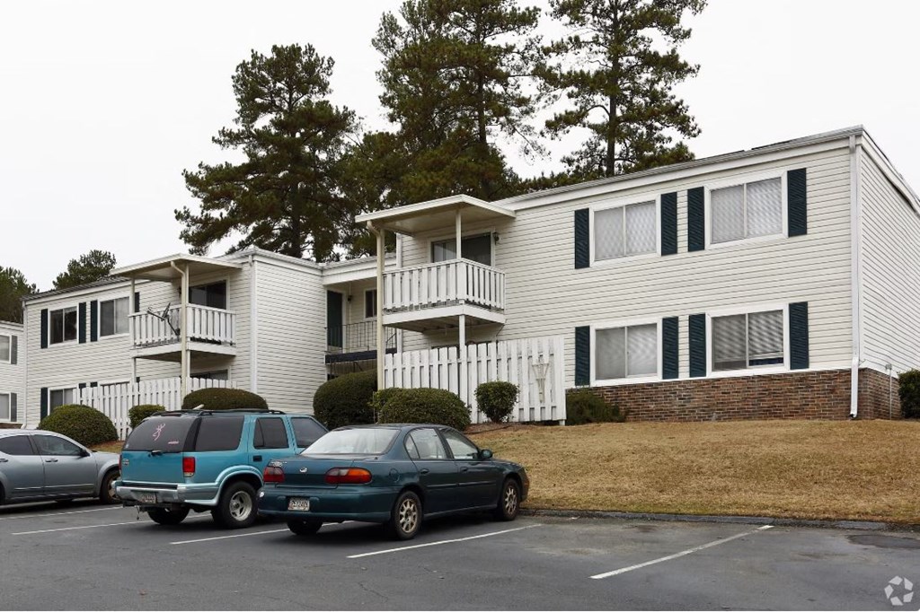 an apartment building with cars parked in a parking lot