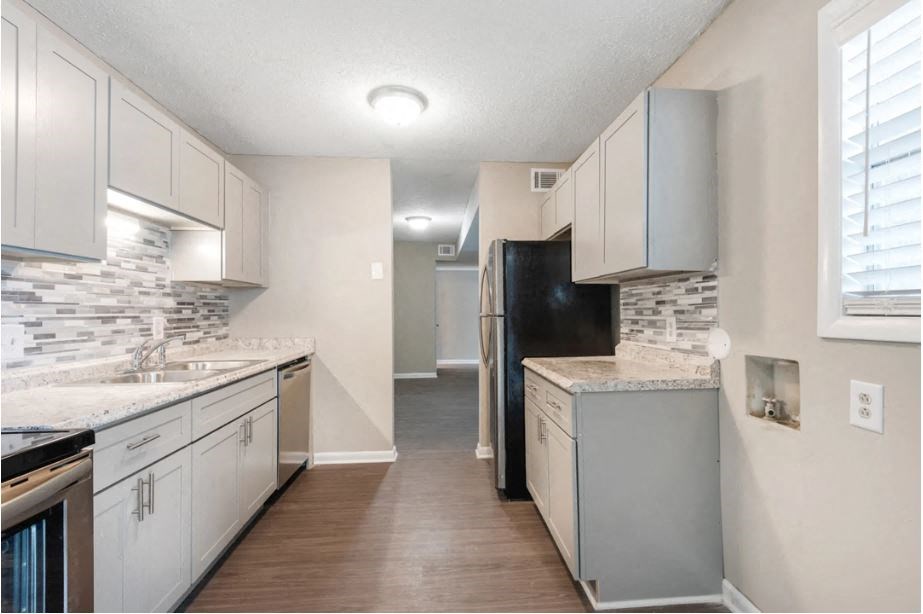 an empty kitchen with white cabinets and a black refrigerator
