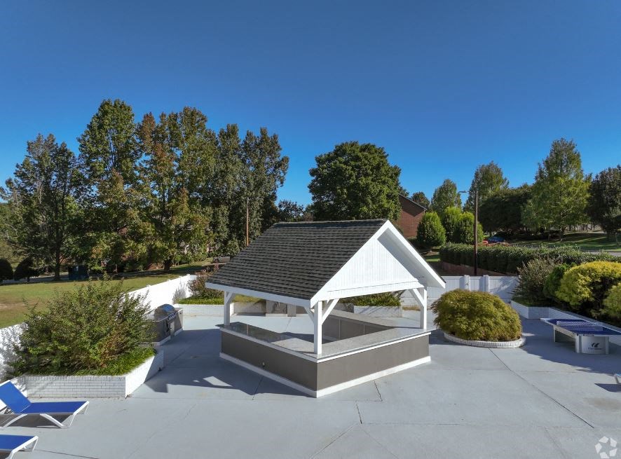 a white pavilion in a park with trees in the background