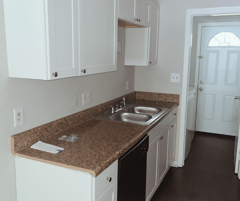 A kitchen with brown granite countertops and white cabinets.