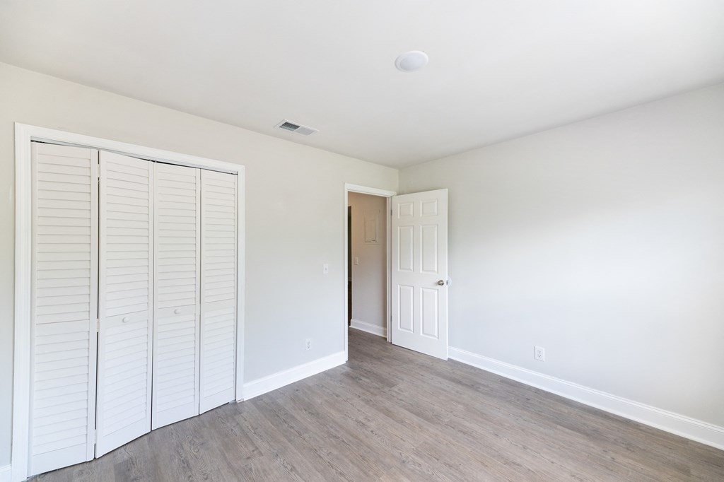 an empty room with a closet and a door to a hallway