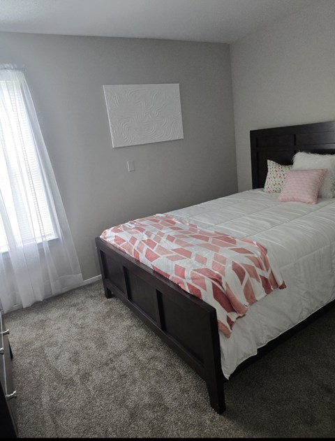 A bedroom with a bed and a window with curtains.