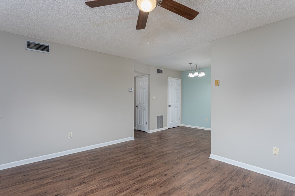 an empty living room with a ceiling fan