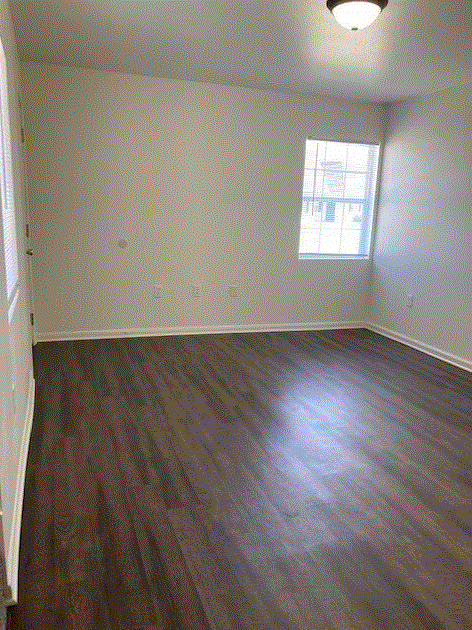 a bedroom with hardwood floors and a window