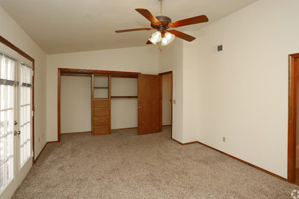 an empty bedroom with a ceiling fan