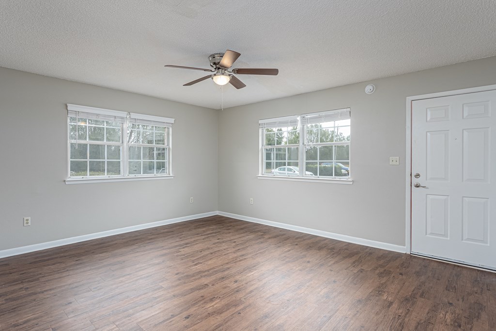 an empty bedroom with a ceiling fan and three windows