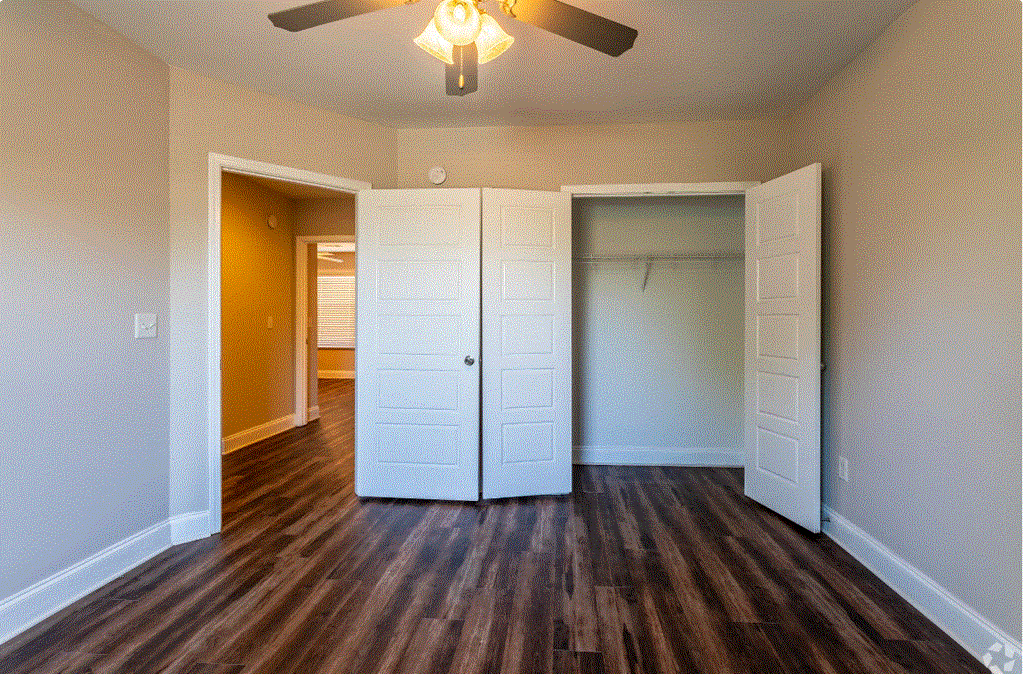 an empty bedroom with a ceiling fan and closet