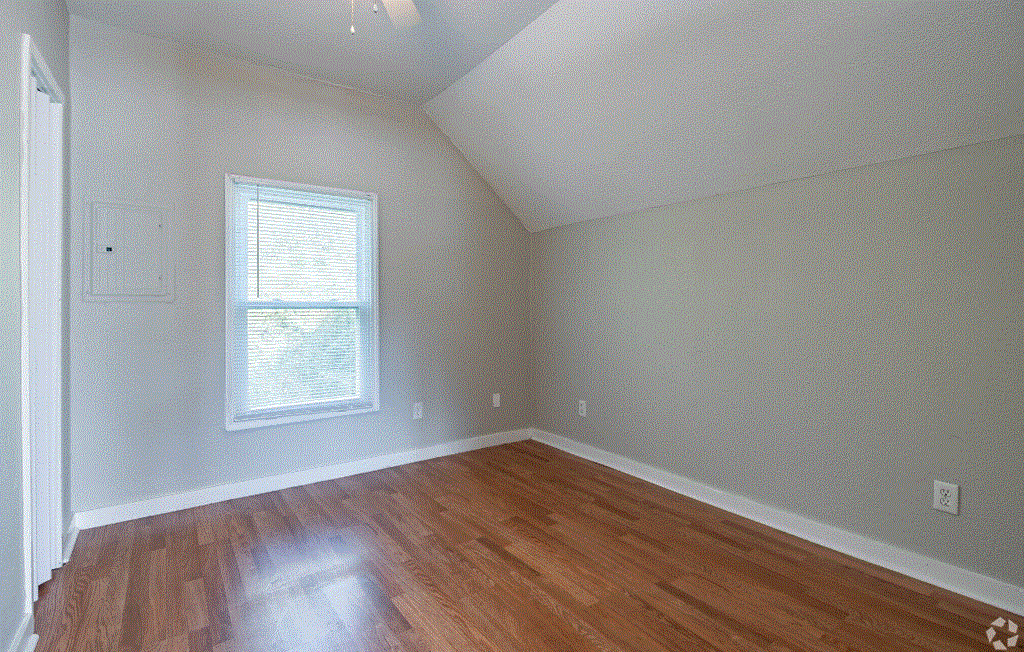 a bedroom with hardwood floors and a window