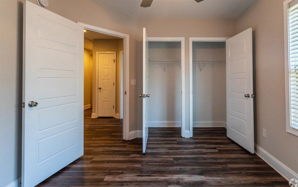 a bedroom with three doors and a closet in the background