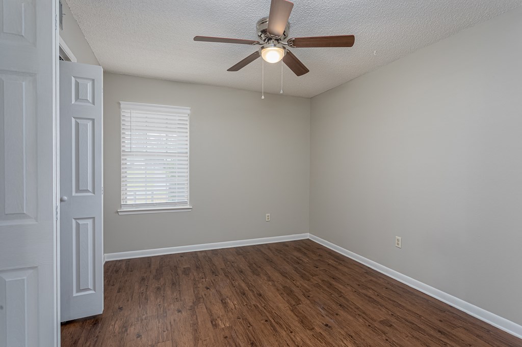 an empty bedroom with a ceiling fan