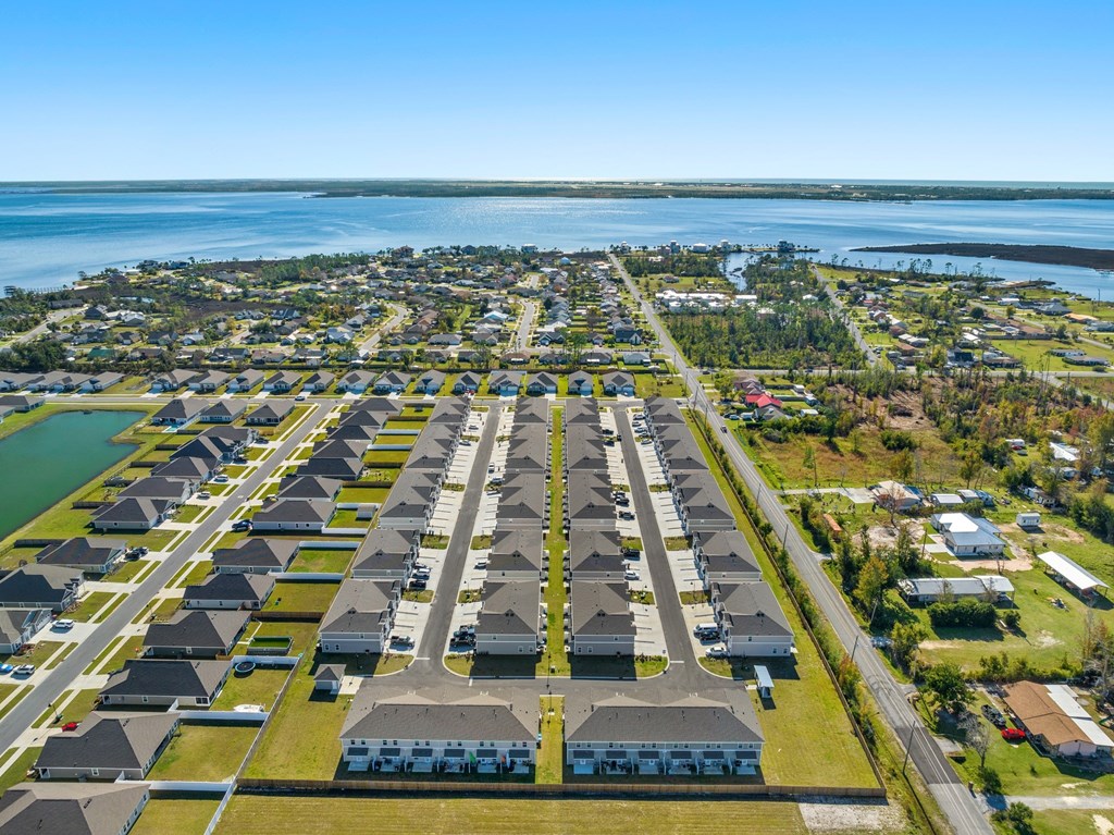 an aerial view of several rows of houses with a lake in the background